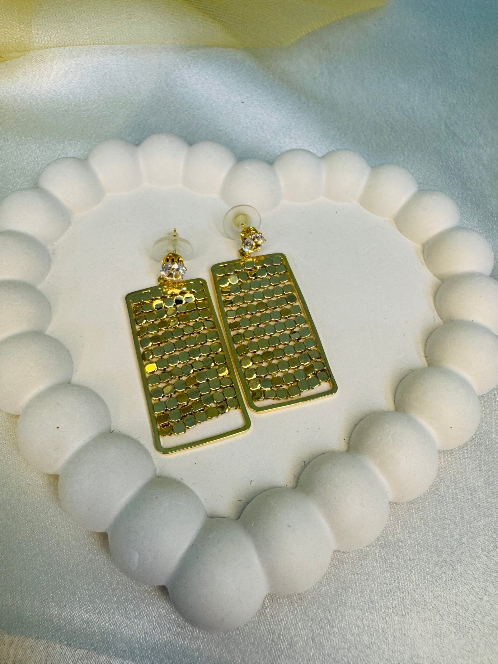 Pair of gold-toned, multi-tiered dangle earrings with an abstract, hammered finish.