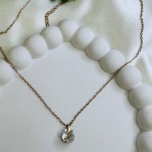 Rose gold-tone chain necklace with a round, clear stone pendant featuring a gold-tone "LV" logo.