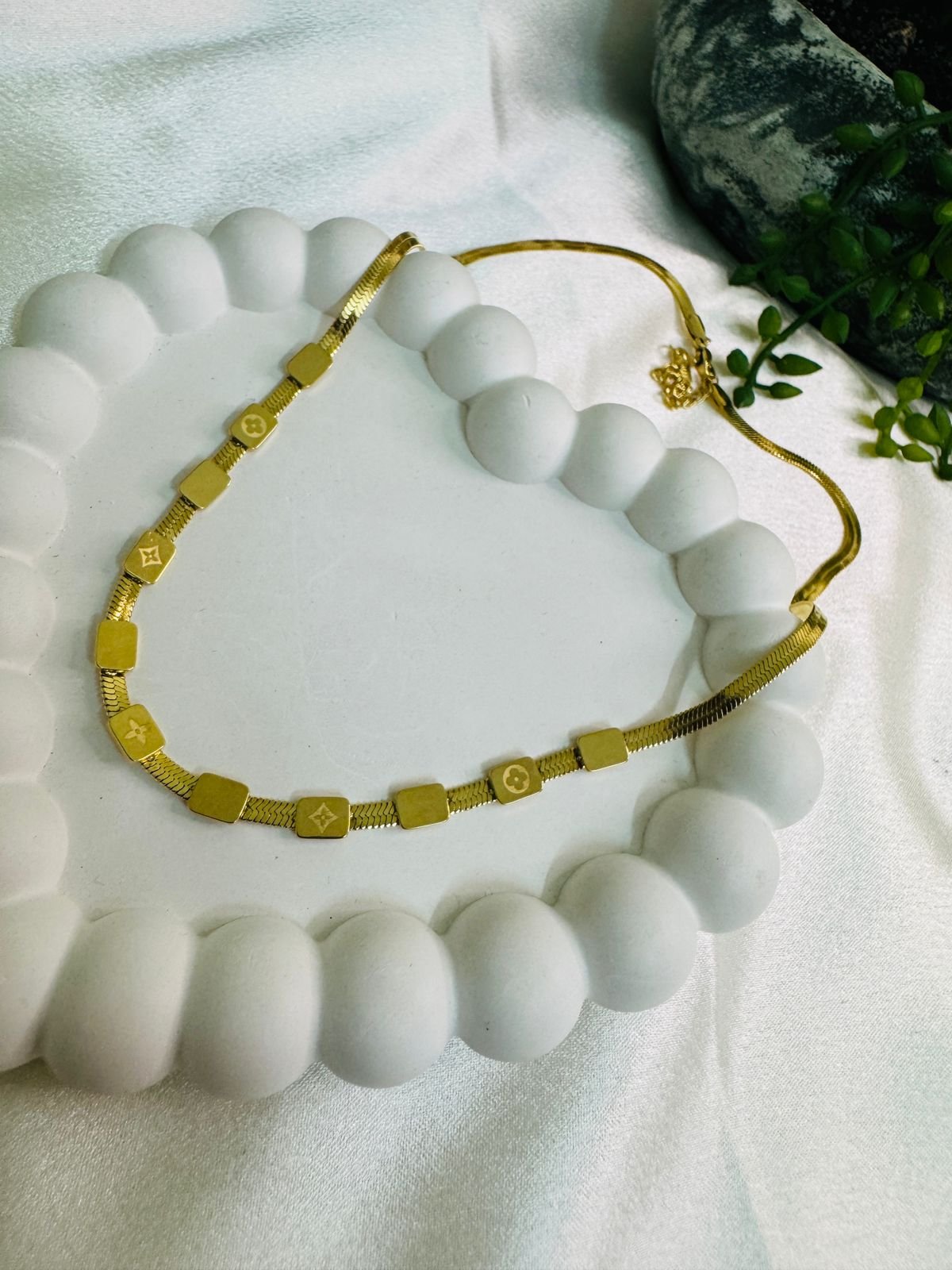 Gold-plated chain with square charms featuring a monogram pattern