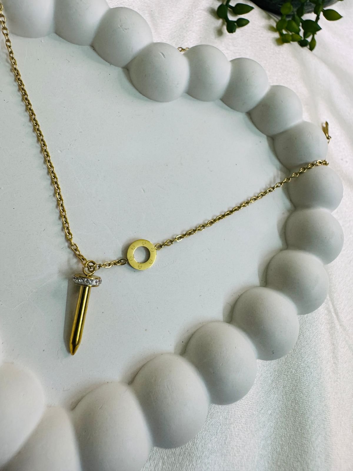 gold-toned pendant necklace with a nail-shaped charm and a small accent stone. - Image 3