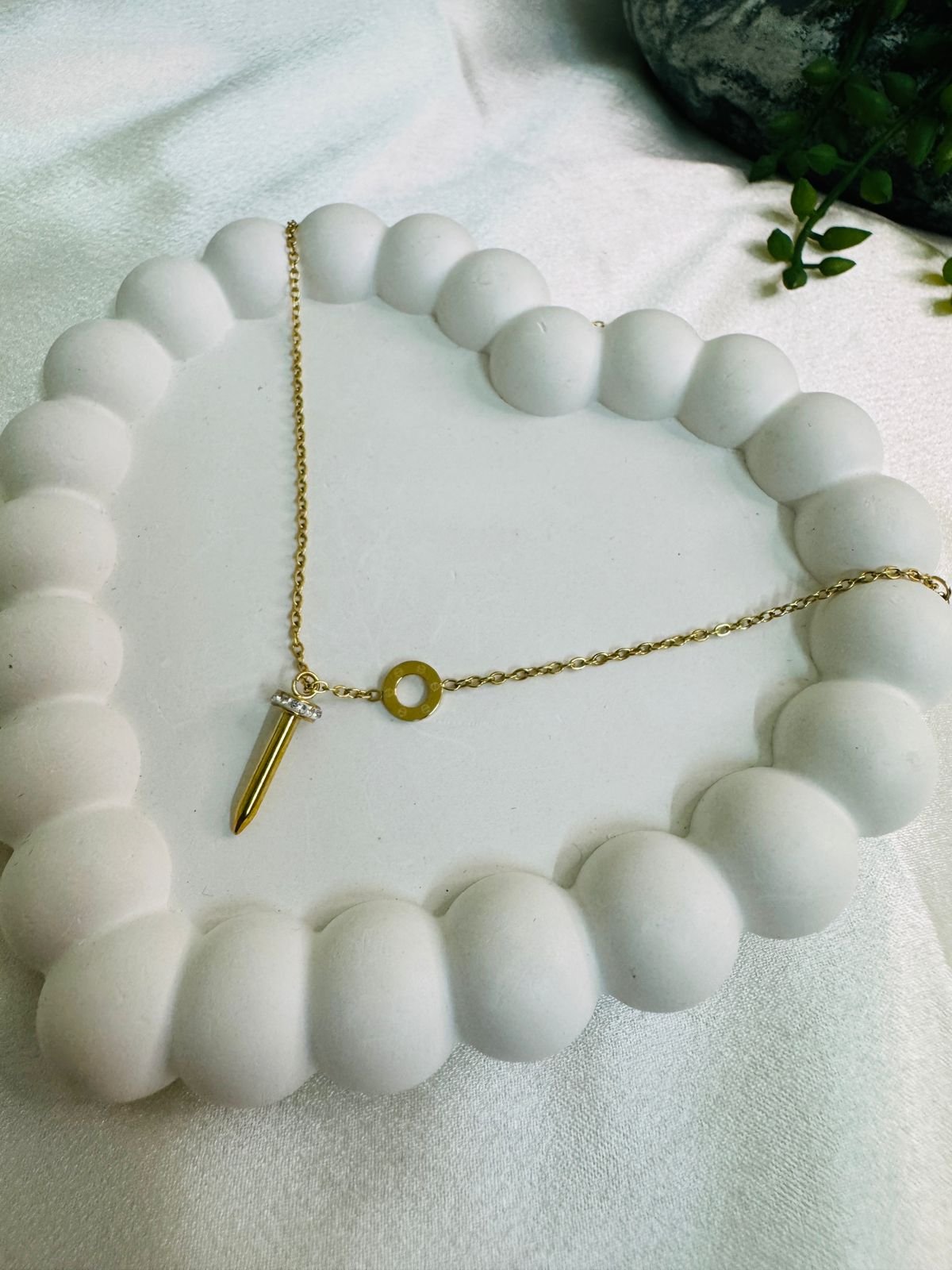 gold-toned pendant necklace with a nail-shaped charm and a small accent stone. - Image 2