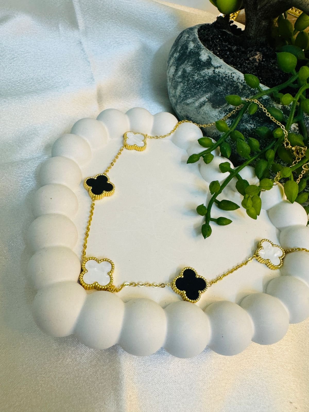 gold-toned, clover-inspired bracelet featuring black and white enamel or mother-of-pearl charms with a beaded edge design. - Image 3