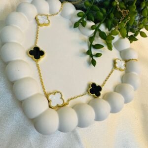 gold-toned, clover-inspired bracelet featuring black and white enamel or mother-of-pearl charms with a beaded edge design.