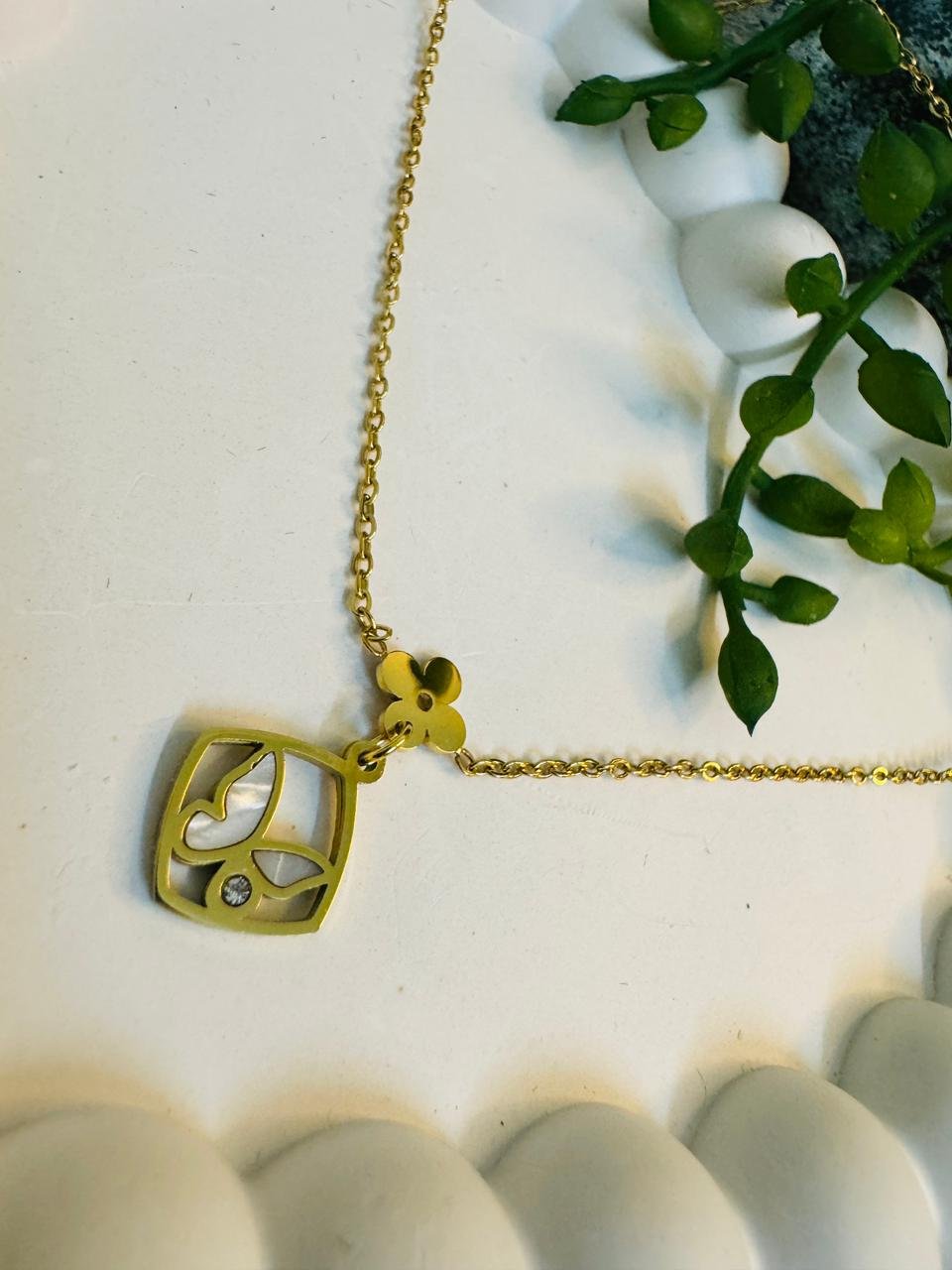 gold-toned necklace with a square butterfly and flower pendant. - Image 3