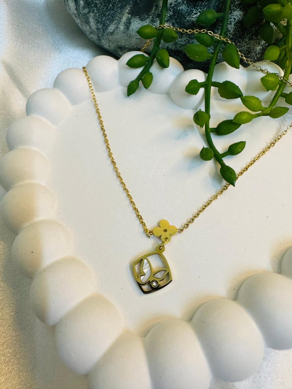 gold-toned necklace with a square butterfly and flower pendant.