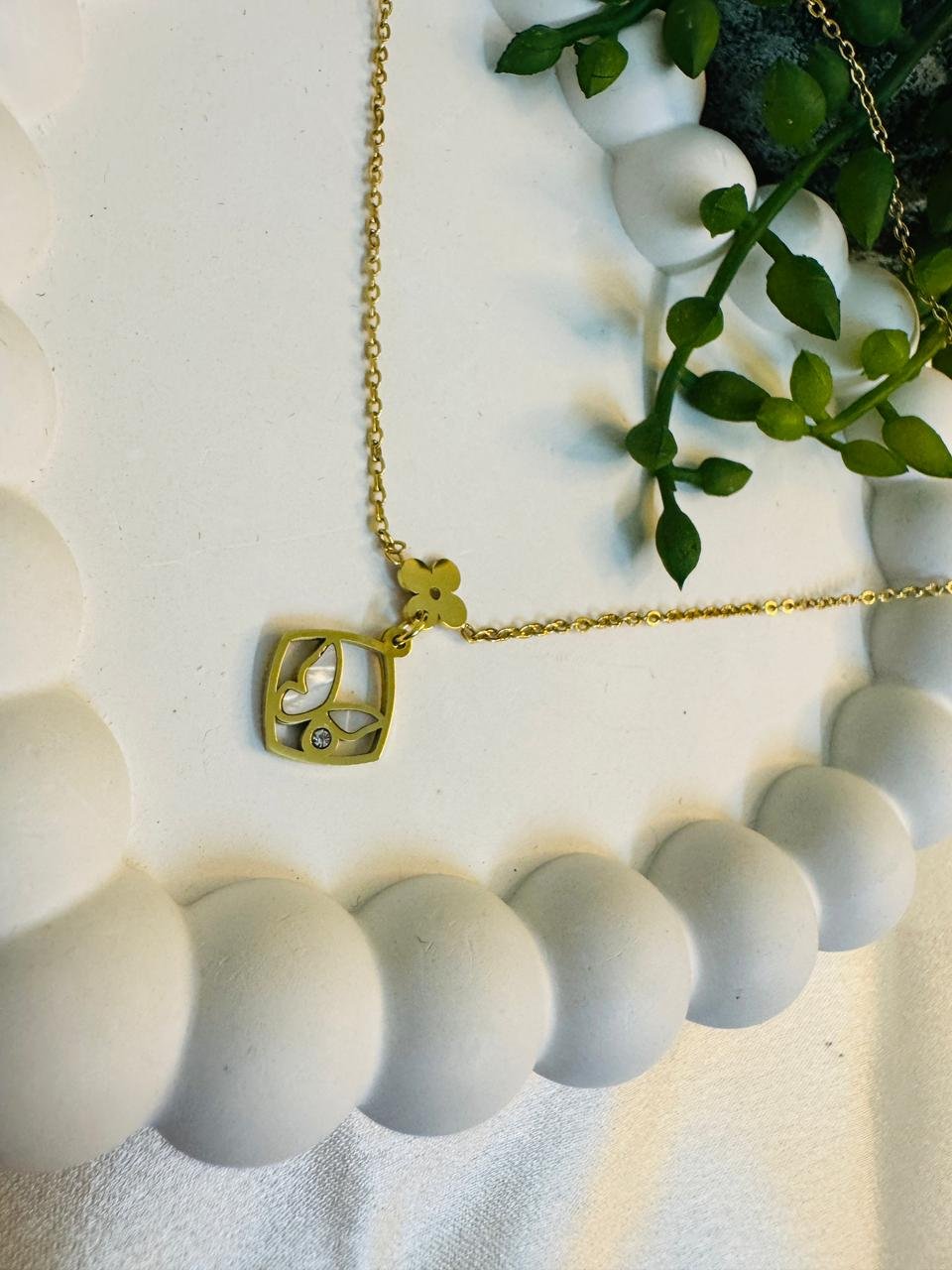 gold-toned necklace with a square butterfly and flower pendant. - Image 2