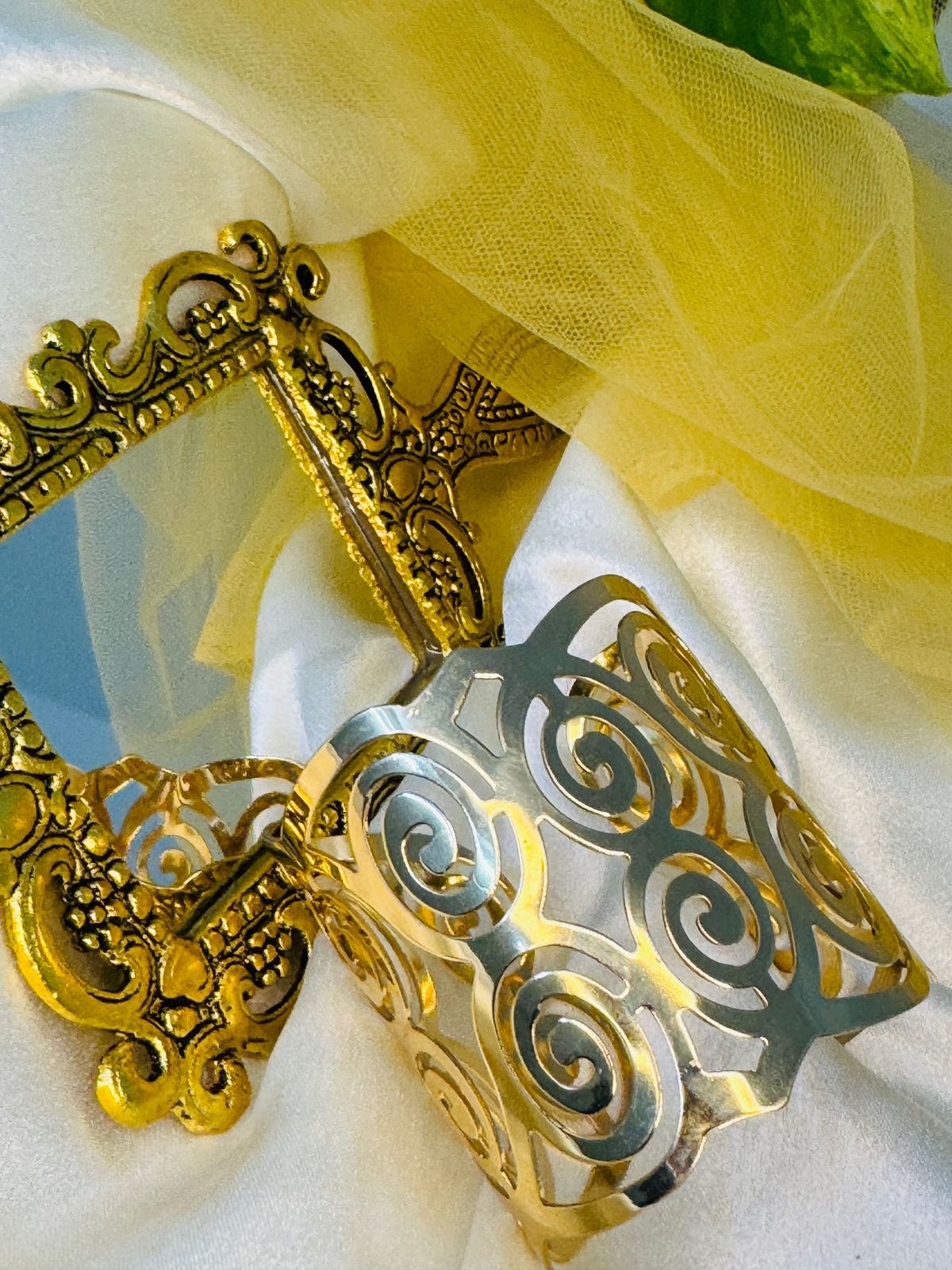 Gold-toned metal napkin ring with a cut-out swirl design.