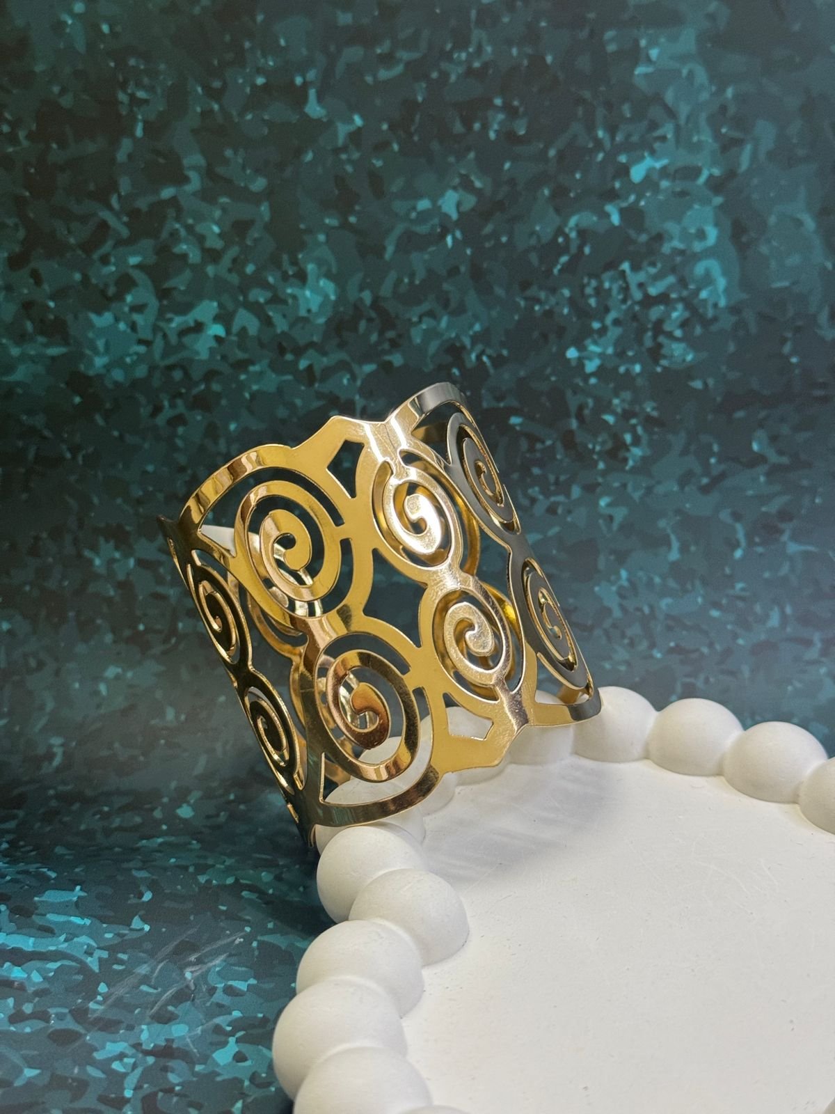 Gold-toned metal napkin ring with a cut-out swirl design. - Image 4