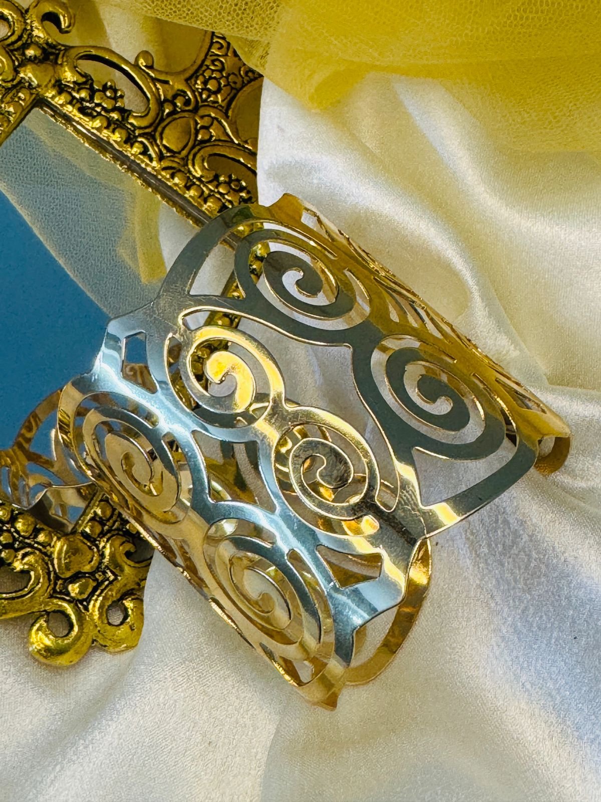 Gold-toned metal napkin ring with a cut-out swirl design. - Image 3