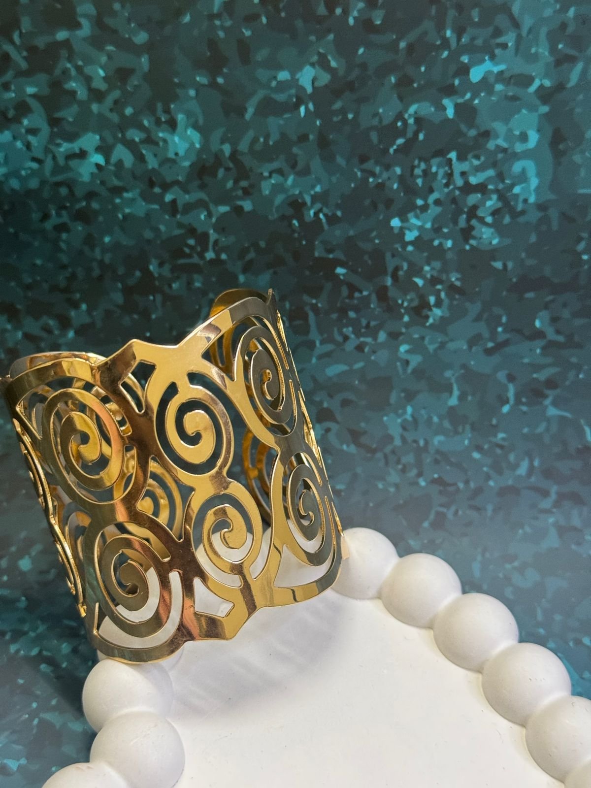 Gold-toned metal napkin ring with a cut-out swirl design. - Image 2