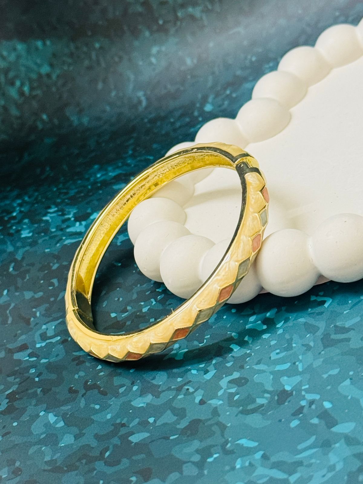 Gold-plated bangle featuring a multi-colored enamel rhombus, or checkered, pattern.