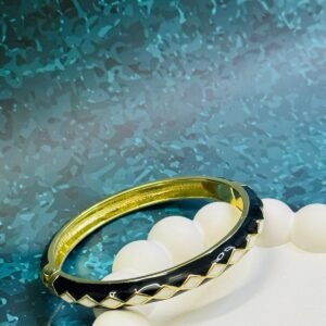 Black and white enamel hinged bangle bracelet with a gold-toned finish.
