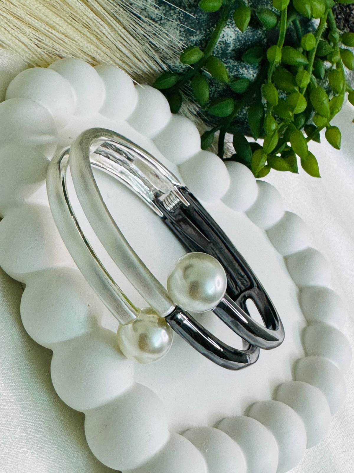 Dual-toned hinged cuff bracelet crafted in metal with faux pearls.